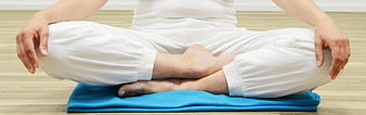 Woman meditating in lotus position on blue cushion