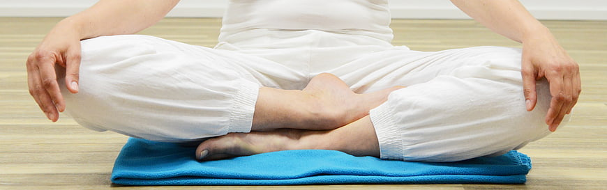 Woman meditating in lotus position on blue cushion