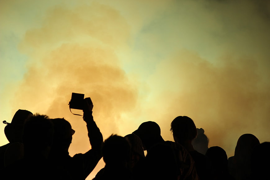 Silhouetted Crowd At Music Festival With Smoke And Golden Sky