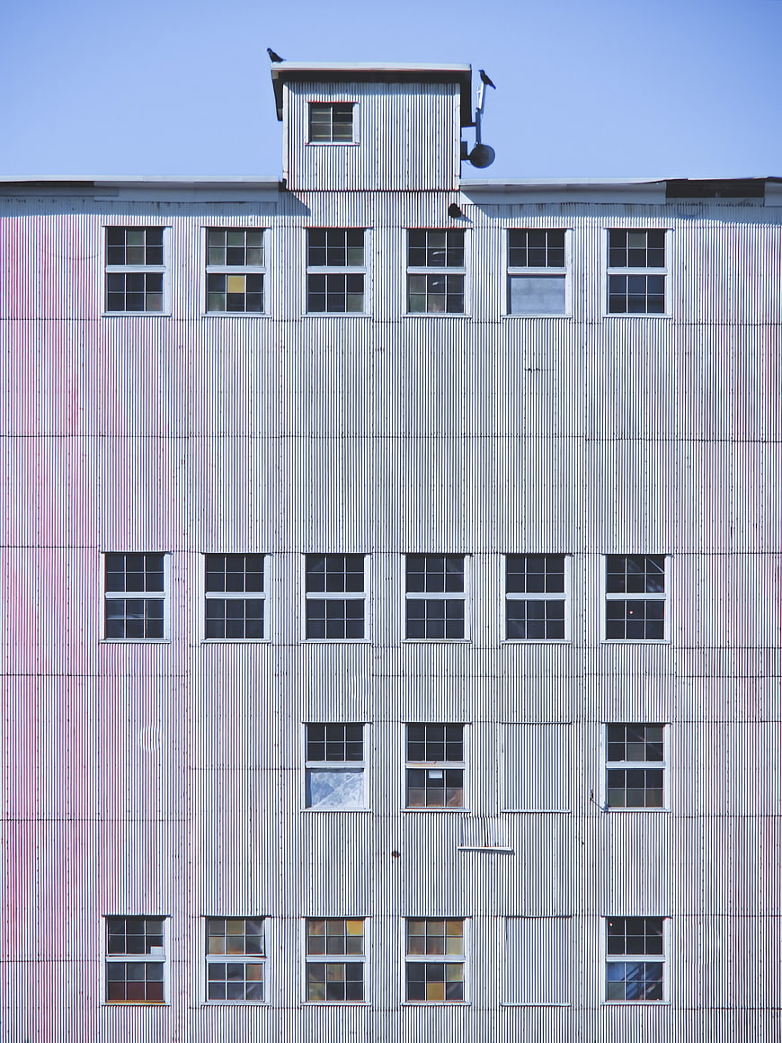 Industrial corrugated metal building facade with grid of windows