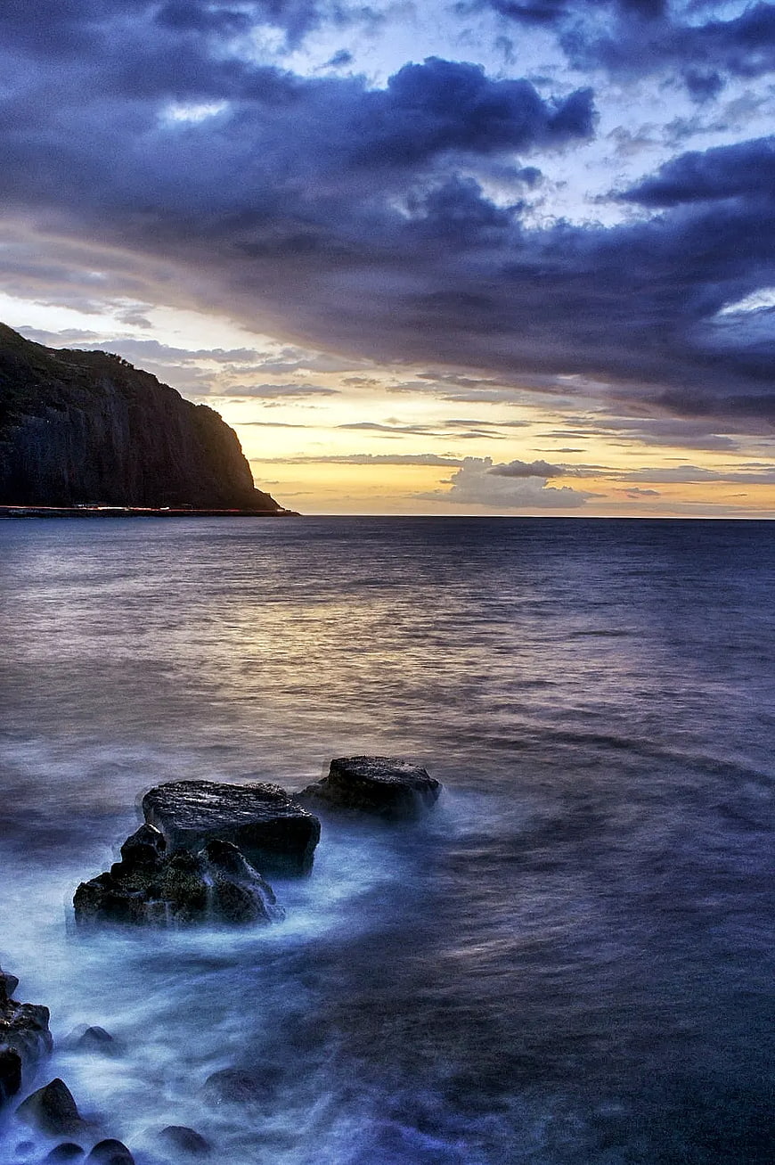 Dramatic Sunset Over Ocean with Cliffs and Rocks