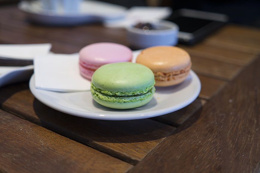 Colorful macarons on a white plate on a wooden table