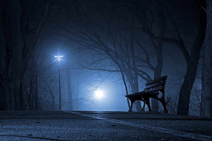 Lonely park bench in foggy night with street lamp