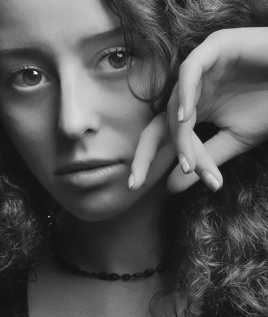 Black and white close-up portrait of a woman with hand on face