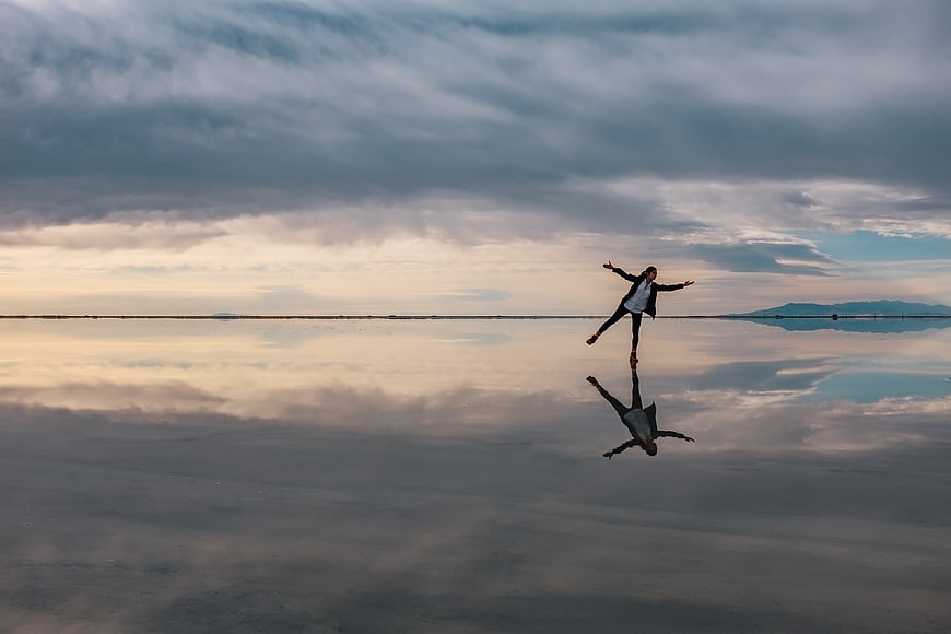 Woman jumping on reflective salt flat at sunset