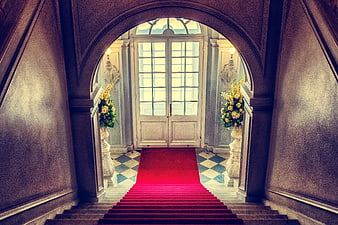 Grand Interior Staircase With Red Carpet Leading To Elegant Entrance