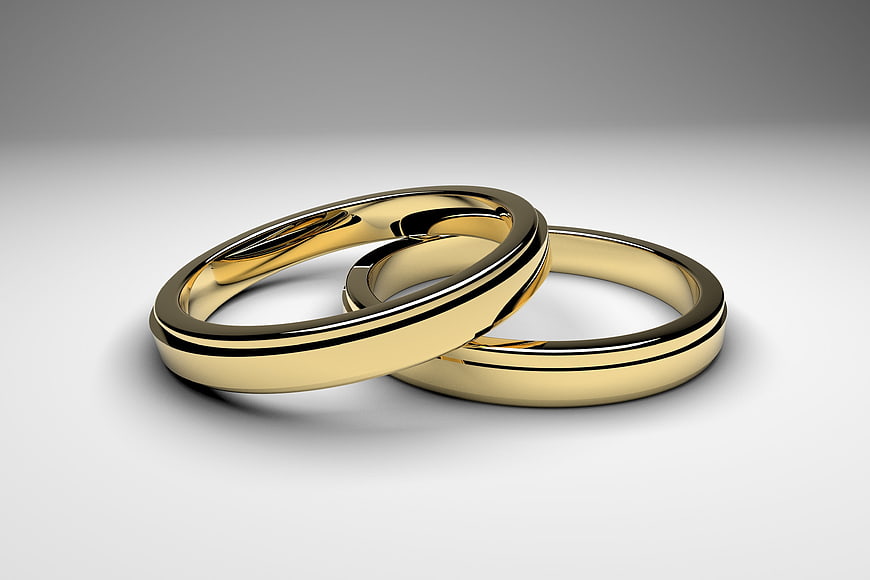 Two interlocking gold wedding rings on a white background