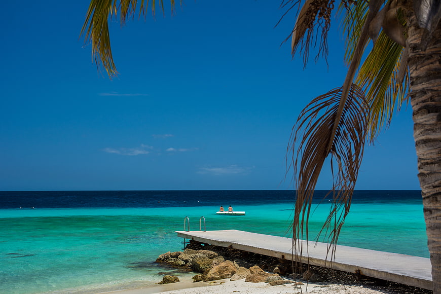 Tropical pier with turquoise water and palm trees in Curacao