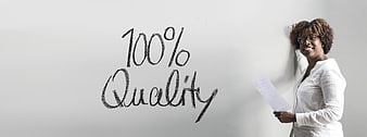 Woman standing next to 100% Quality written on whiteboard