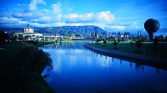 Wide landscape of park with lake, mountains, and large sphere sculpture