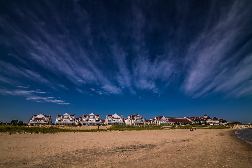 Luxury beachfront villas under dramatic blue sky with wispy clouds