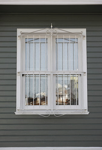 White Window with Iron Bars on Gray House Exterior