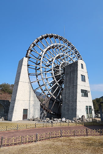 Giant wooden water wheel structure against blue sky