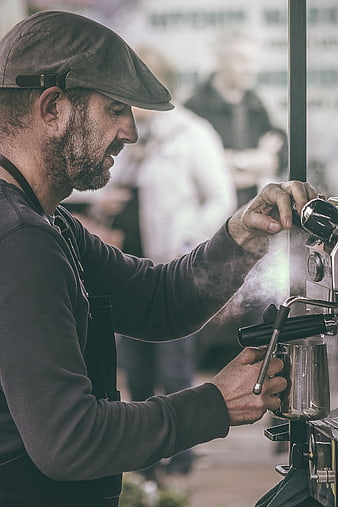 Barista steaming milk with espresso machine in cafe
