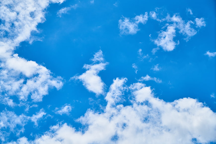 Bright Blue Sky with Fluffy White Clouds Background
