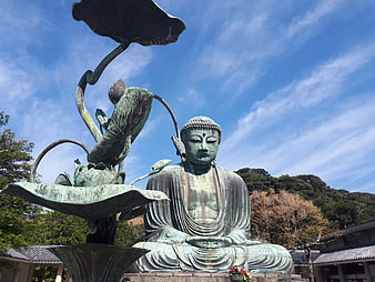 Bronze Buddha Statue with Lotus Sculpture Against Blue Sky