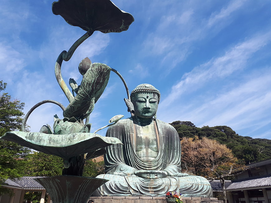 Bronze Buddha Statue with Lotus Sculpture Against Blue Sky