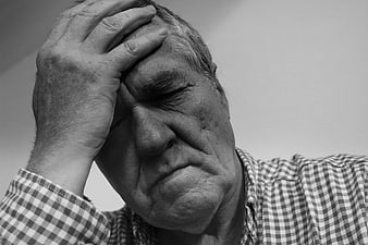 Senior man holding head in despair and exhaustion