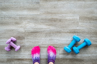 Top view of feet in colorful socks with dumbbells on wooden floor