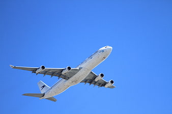 Large white airplane ascending against a clear blue sky