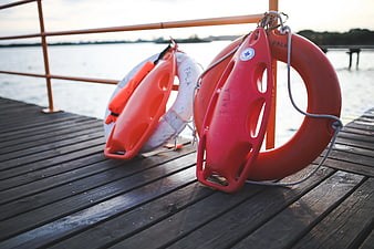 Red and white lifebuoys on wooden pier railing