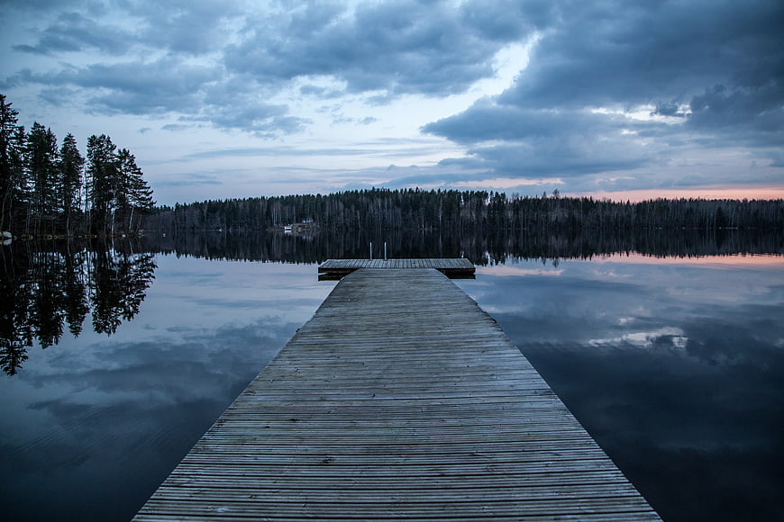 Serene Wooden Dock on Calm Lake at Dusk with Reflections