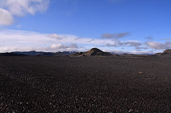 Vast black volcanic sand desert landscape with distant mountains