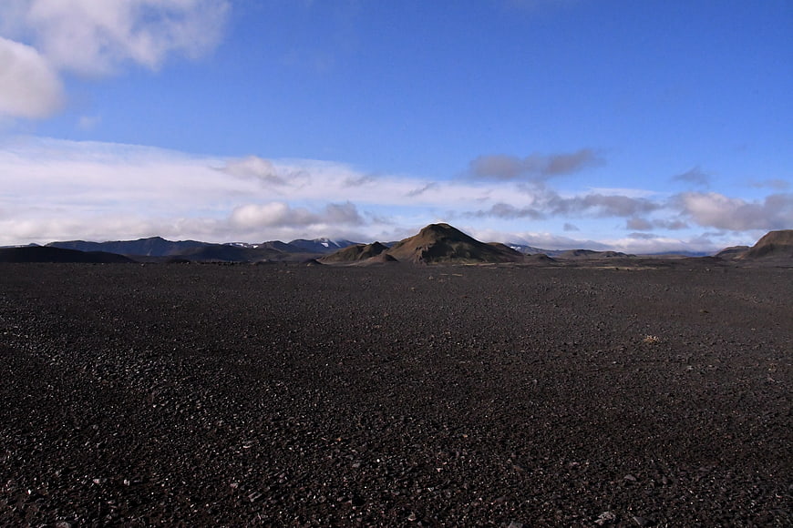Vast black volcanic sand desert landscape with distant mountains