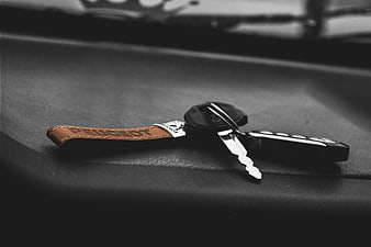 Peugeot car keys on black dashboard with leather keychain