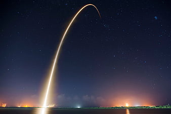 Rocket Launch Light Trail Arcing Over Night Sky
