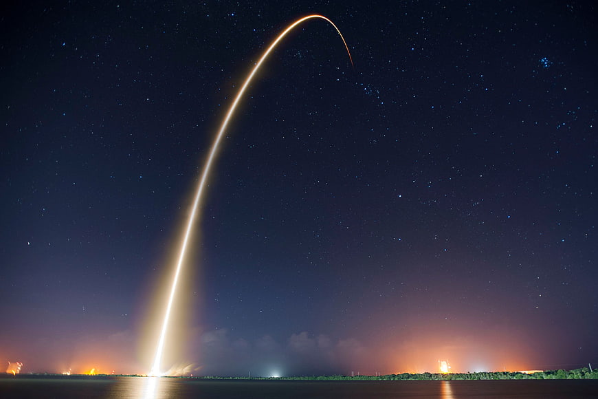 Rocket Launch Light Trail Arcing Over Night Sky