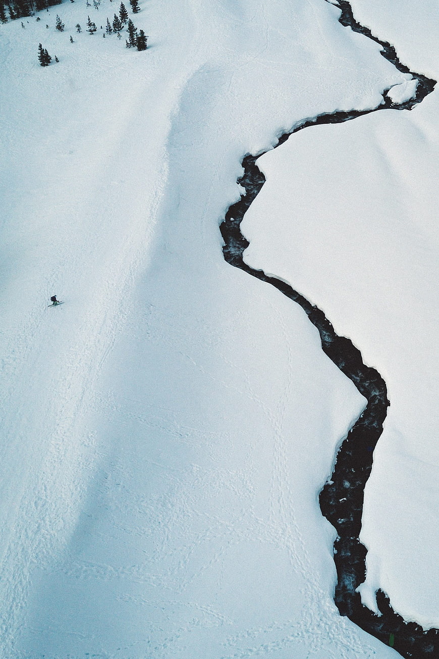Aerial view of skier on snowy slope near frozen river