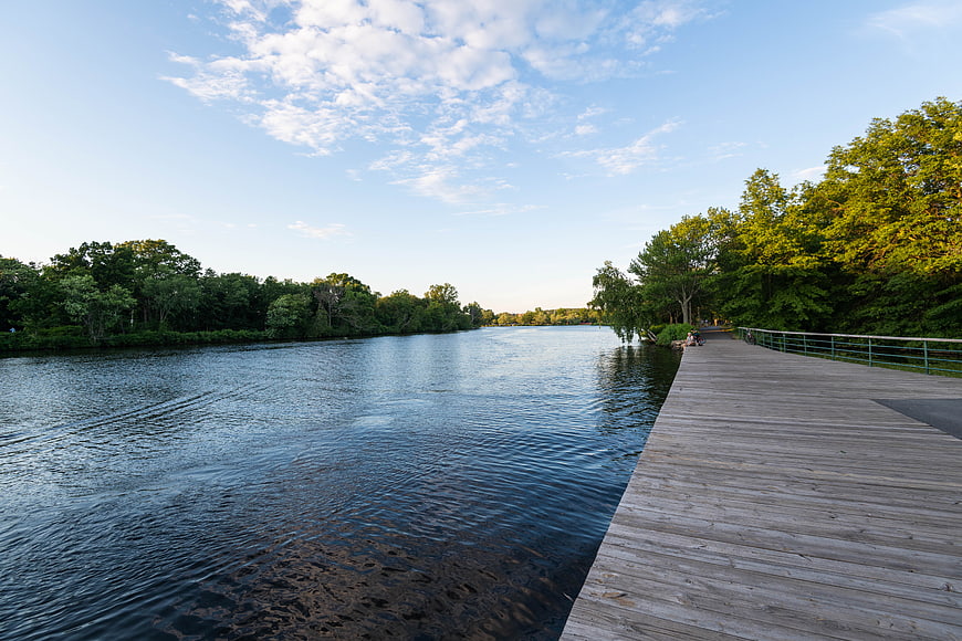 Serene Wooden Dock Extending Over Calm River with Blue Sky