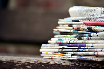 Stack of folded newspapers on a rustic wooden table