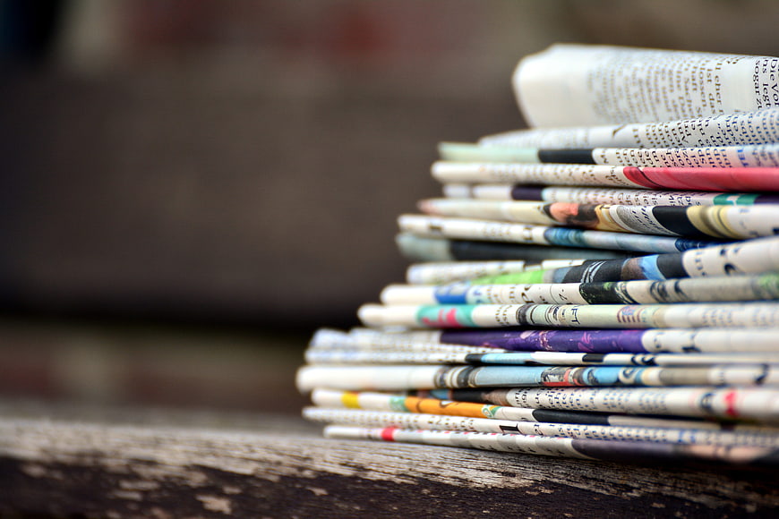Stack of folded newspapers on a rustic wooden table