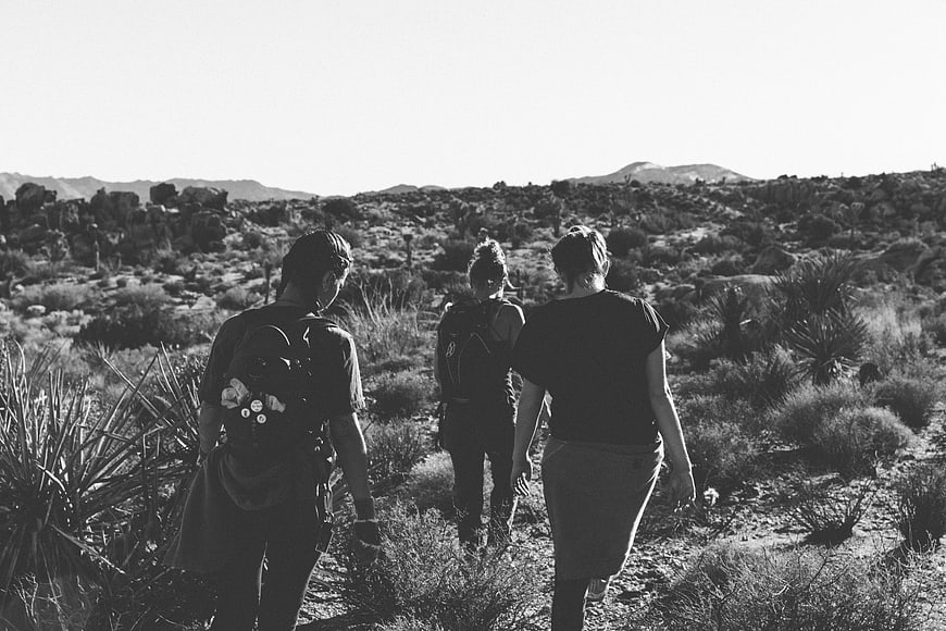 Three women hiking through desert landscape in black and white