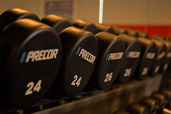 Row of black Precor dumbbells on gym rack