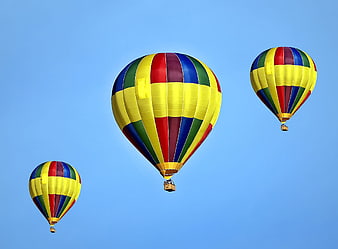 Three colorful hot air balloons flying in blue sky