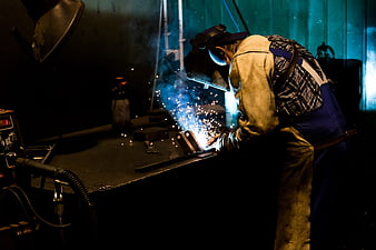 Industrial Welder Working With Sparks In Dark Factory Workshop