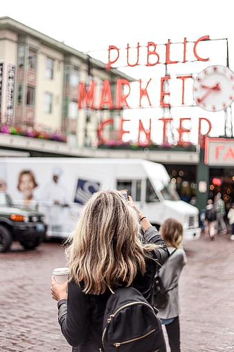 Woman taking photo of Pike Place Market sign in Seattle