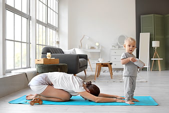 Mother doing yoga with toddler in bright living room