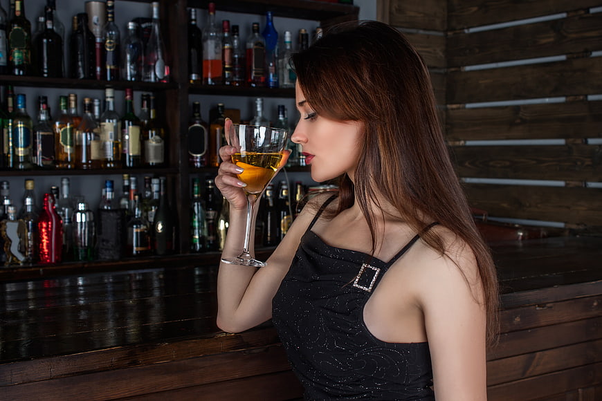 Woman holding cocktail glass in dimly lit bar
