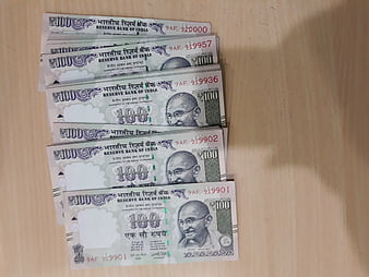 Stack of Indian 100 Rupee Notes on Wooden Table