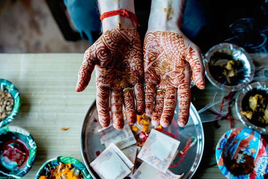 Hands with intricate henna designs over ritual offerings