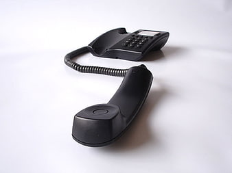 Black landline telephone with handset off hook on white background