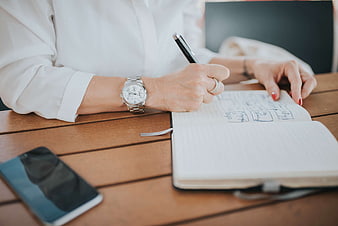 Woman Writing in Notebook at Wooden Table
