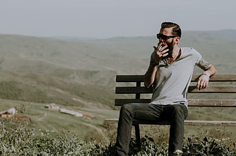 Man Smoking on Bench with Scenic Mountain View