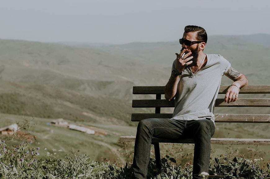 Man Smoking on Bench with Scenic Mountain View