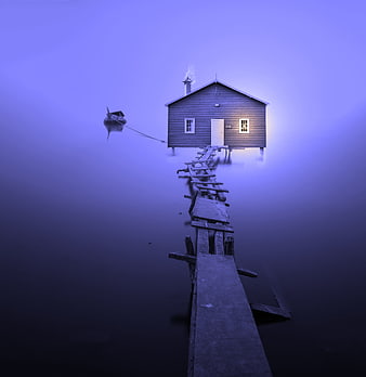 Lonely wooden cabin on a foggy lake with a broken pier