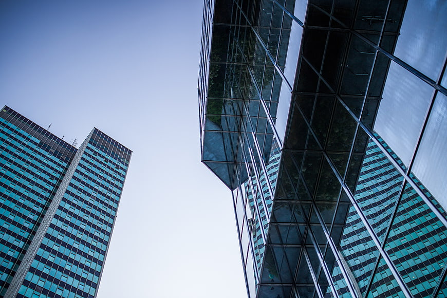 Low angle view of modern glass skyscrapers against blue sky